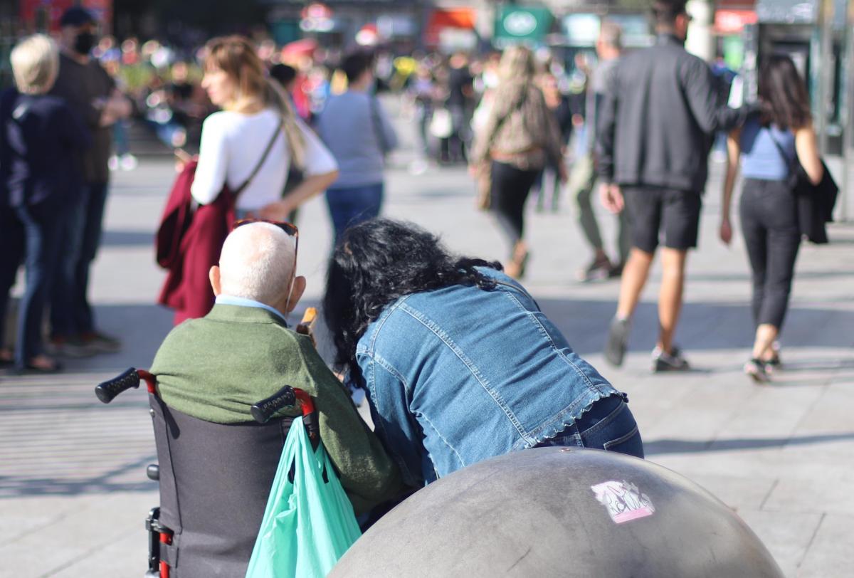 Cuidadora con un anciano en la Puerta del Sol de Madrid